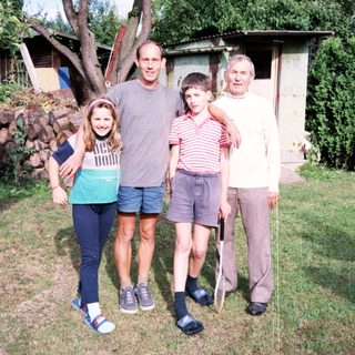 Family posing outdoors near rustic cabin.