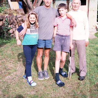 Family posing outdoors near rustic cabin.