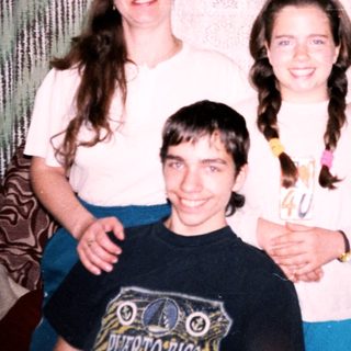 Family posing indoors with a birthday cupcake.