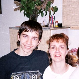 Family photo with three smiling individuals indoors.
