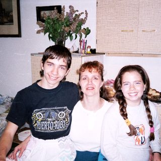 Family photo with three smiling individuals indoors.