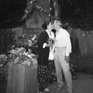Couple sharing affectionate moment near statue.