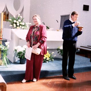 Religious ceremony with woman reading and man holding cup.