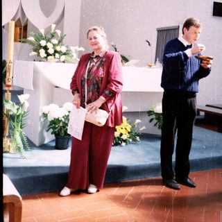 Religious ceremony with woman reading and man holding cup.
