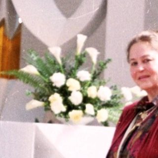Woman in red standing at church altar.