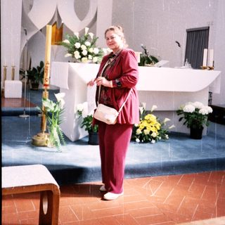 Woman in red standing at church altar.