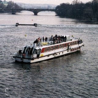 Riverboat tour with historic cityscape in background.