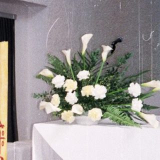 Man in white coat standing in church.