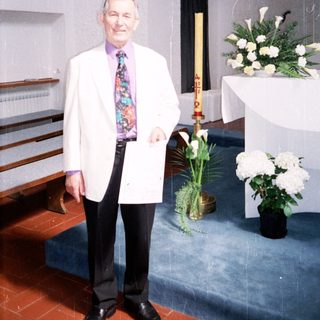 Man in white coat standing in church.