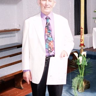 Man in white coat standing in church.