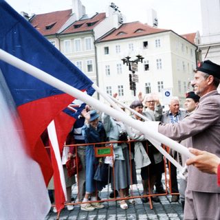 People holding Czech flag in public celebration.