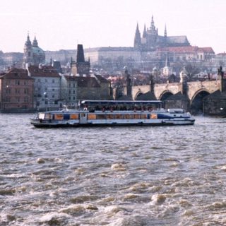 Man posing by Prague Castle with Charles Bridge and Vltava River.