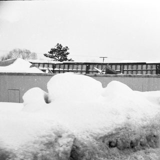 Heavy snow accumulation near industrial building.
