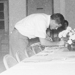 Funeral service with a casket draped in flowers.