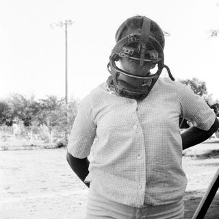 Catcher in baseball gear standing outdoors.