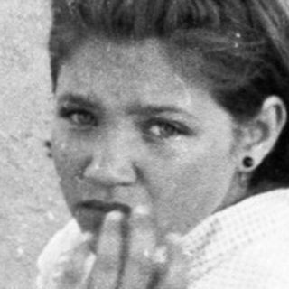 Woman sitting on dugout bench during baseball game.
