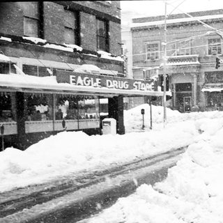 Snow-covered city street with closed Eagle Drug Store.