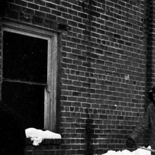 People shoveling heavy snow outside a building.