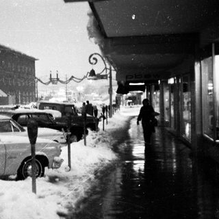 Snowy street scene with parked vintage cars.
