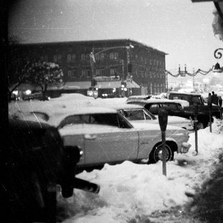 Snowy street scene with parked vintage cars.