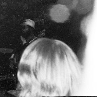 Live band performing on stage with audience raising hands.
