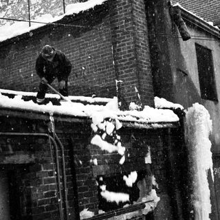 Person clearing snow from rooftop.