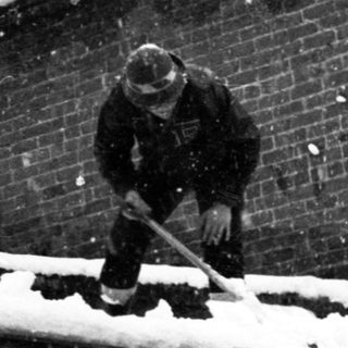 Person clearing snow from rooftop.