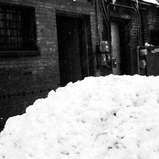 Heavy snow accumulation outside industrial brick building.