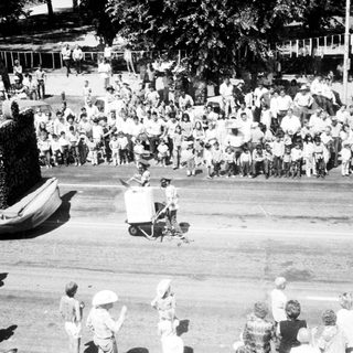 Large crowd watching parade float with giant character.