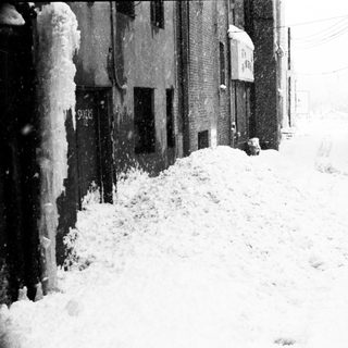 Snow-covered urban street during heavy snowfall.