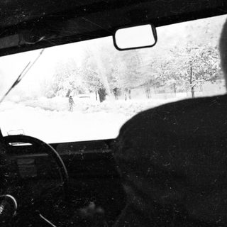 Snow-covered road with blurred winter scenery from inside a car.