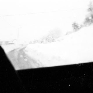 Snow-covered landscape viewed from inside vehicle.