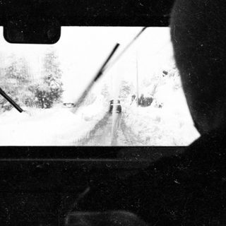 Snow-covered road view from inside vehicle.