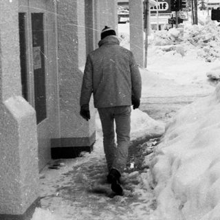 Man walks through snow-covered city street.