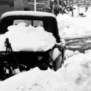 Snow-covered street scene with person walking near historic building.