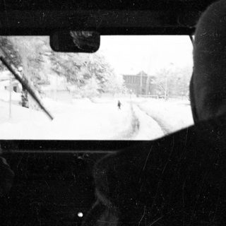 Snowy scene viewed through car windshield.