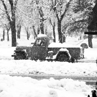 Snow-covered street with parked vintage truck.