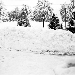 Snow-covered landscape with buried road and footprints.