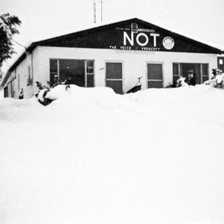 Snow-covered building with "NOT The Voice of Prescott" sign.