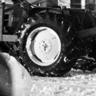 Snow-covered street with damaged vehicles and utility poles.