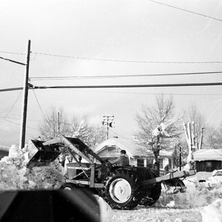 Snow-covered street with damaged vehicles and utility poles.
