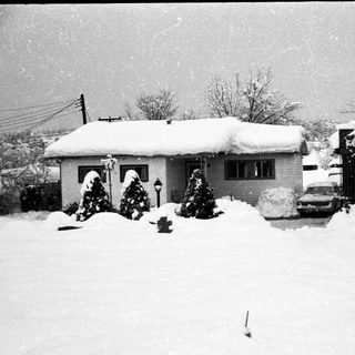 Snow-covered suburban house with Christmas decorations.