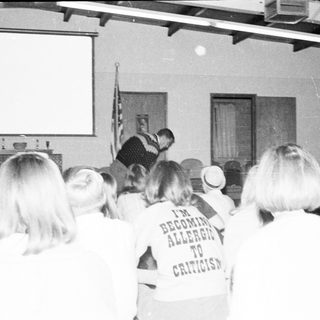 People attending a lecture or event wearing humorous shirts.