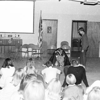 School assembly with performer and students.