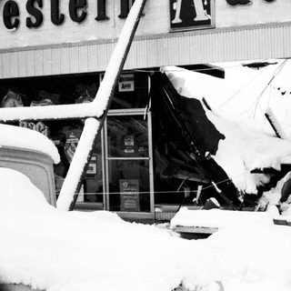 Heavy snow damage to storefront and signage.