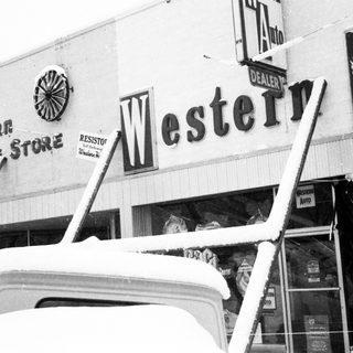"Snow-covered Western Auto storefront with damaged signage."