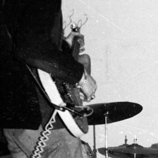 Band performing live with keyboard, drums, and guitar.
