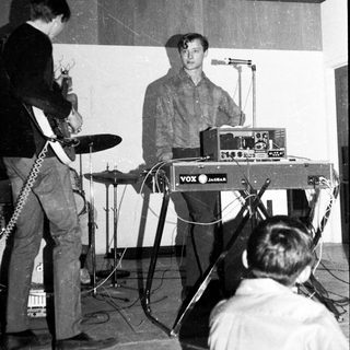 Band performing live with keyboard, drums, and guitar.