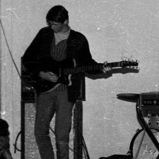 Band performing live with guitars, keyboard, and vocals.