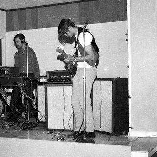 Band performing live with guitars, keyboard, and vocals.